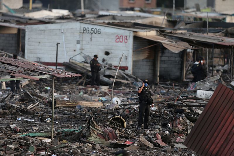 Un policía habla por teléfono entre las casas y puestos de venta destruidos por la tremenda explosión en el mercado de San Pablito, en Tultepec.