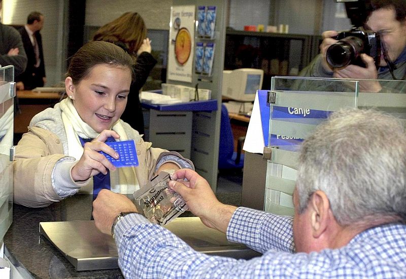 Una niña compra un paquete con monedas de Euro en una oficina bancaria, en Madrid, en diciembre de 2001.