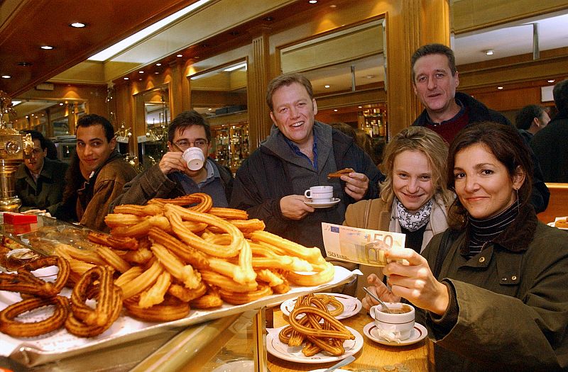 Una joven muestra el billete de euro con el que, por primera vez en la historia,se dispone a pagar el desayuno, los típicos churros con chocolate posteriores a la celebración del año nuevo, el 1 de enero 2002.