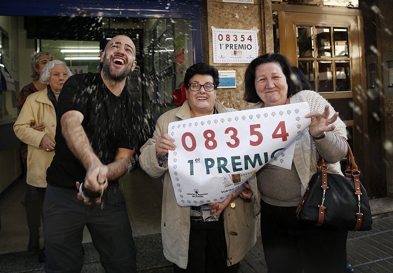 Agraciados con el primer premio del sorteo de El Niño, dotado con 2.000.000 de euros a la serie, lo celebra con el número en la mano, en las puertas de la administración número 3 de Torrent, Valencia.