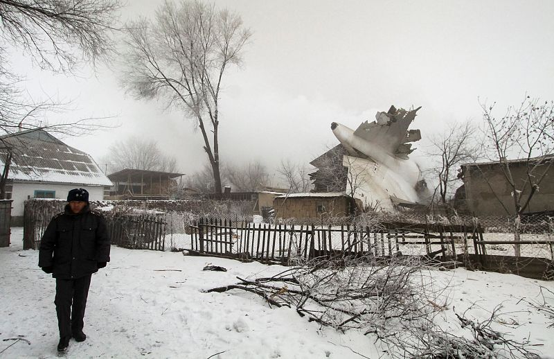 Un policía vigila el lugar donde se ha estrellado un avión de carga en Kirguistán