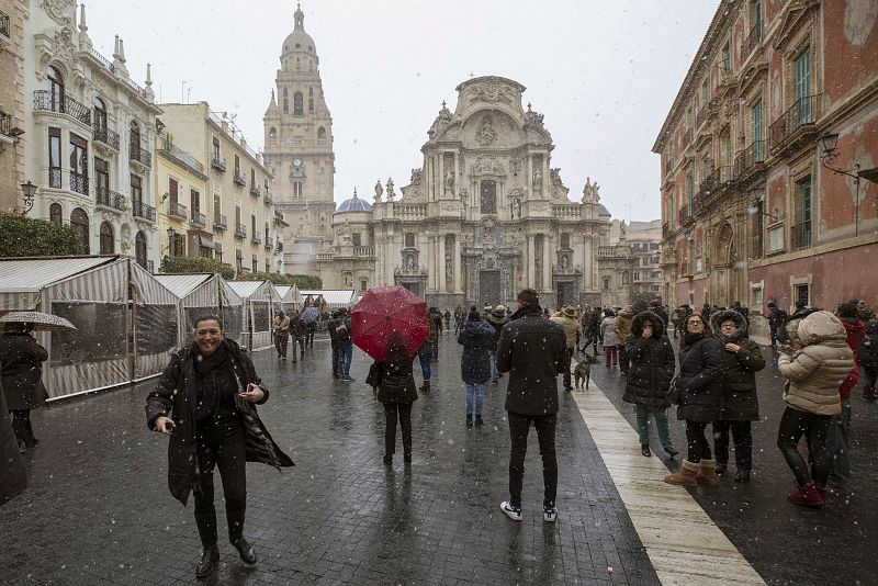 Varias decenas de personas observan la nevada caída esta mañana en Murcia, en la Plaza Cardenal Belluga.