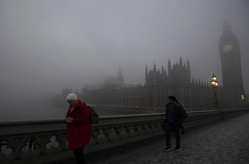 Peatones cruzan el puente de Westminster en Londres envueltos por la niebla