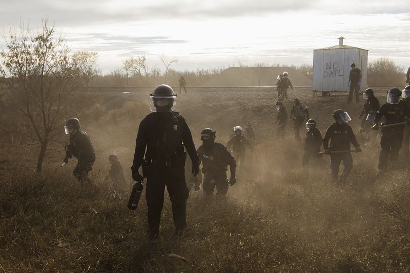 La imagen muestra a un grupo de policías antidisturbios que tratan de dispersar con balas de goma a los manifestantes que protestan en una carretera secundaria junto al oleoducto Dakota Access Pipelines, en Estados Unidos.