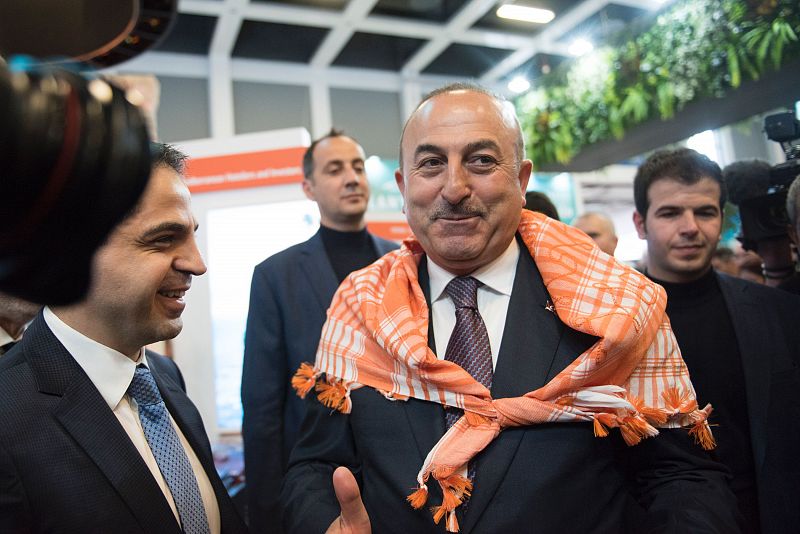 El ministro de Exteriores turco Mevlut Cavusoglu posa con un pañuelo tradicional de la ciudad de Antalya durante su visita a la Feria Internacional de Turismo ITB de Berlín.