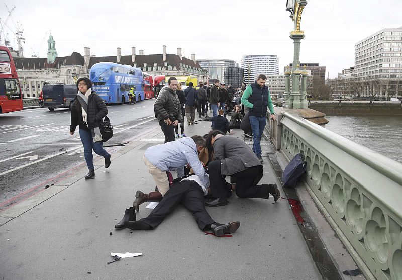 Varias personas heridas son atendidas en la acera a lo largo del puente de Westminster, en pleno centro de Londres, junto a la sede del Parlamento británico, tras el incidente.