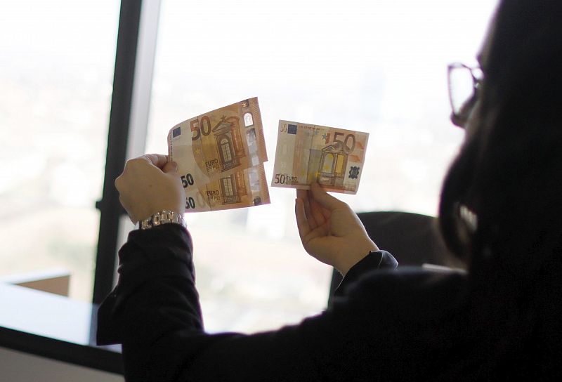 Una mujer observa dos billetes nuevos de 50 euros junto a uno de la serie original durante una presentación en Alemania.
