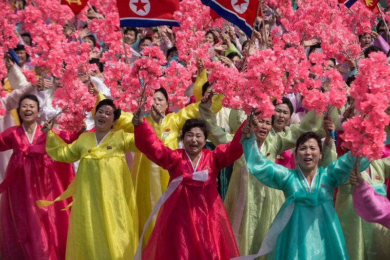 Mujeres con el traje tradicional coreano portan flores al pasar junto a su líder Kim Jong-un