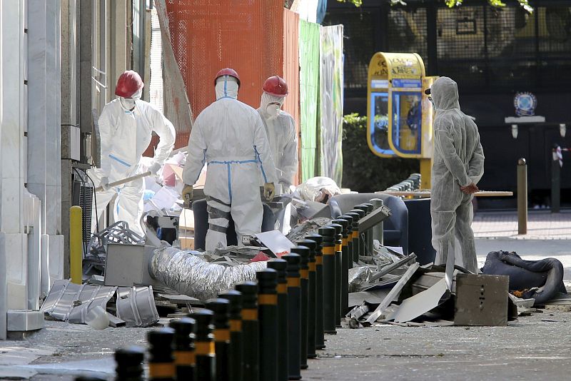 Agentes de la policía científica examinan el exterior de unas oficinas del banco Eurobank en Atenas donde el miércoles explotó una bomba sin causar víctimas.