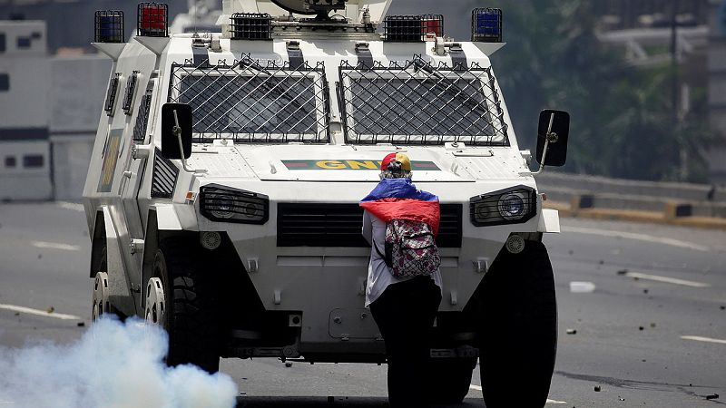 Una manifestante de la oposición bloquea una tanqueta de la Policía durante la manifestación contra Maduro en Caracas, Venezuela