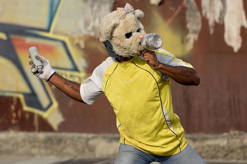 Un manifestante lanza de vuelta una bomba de gas lacrimógeno hacia la policía