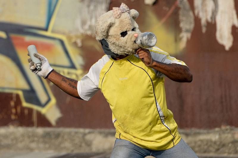 Un manifestante lanza de vuelta una bomba de gas lacrimógeno hacia la policía