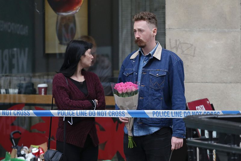 Una pareja con un ramo de flores tras el cordón policial situado en el extremo norte del Puente de Londres, en tributo de las víctimas del atentado