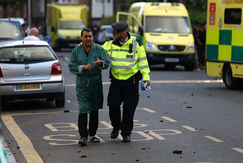 Un policía ayuda a un vecino evacuado de la Torre Grenfell. Al menos 30 personas han resultado heridas y podría haber aún vecinos atrapados en el edificio.