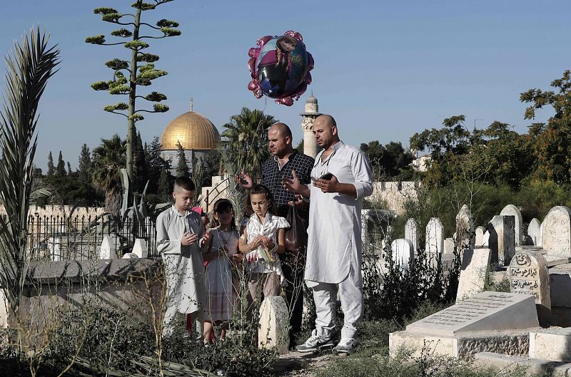 Palestinos oran en un cementerio musulmán cerca de la mezquita de Al Aqsa y la Cúpula de la Roca, en Jerusalén, Palestina.