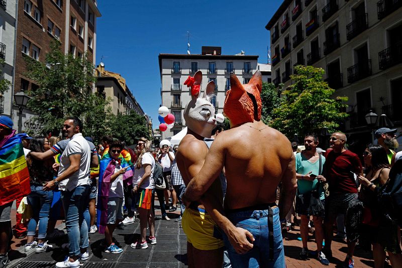 Dos hombres con máscaras aguardan en la plaza de Chueca el inicio del desfile del World Pride 2017