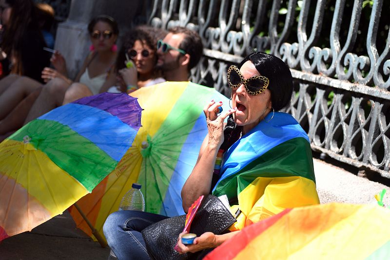 La gente aguarda sentada el paso de la manifestación del 'Orgullo' en Madrid