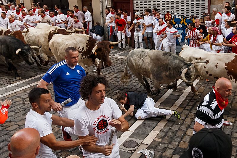 Un corredor resbala frente a los toros en la  curva de los mercaderes