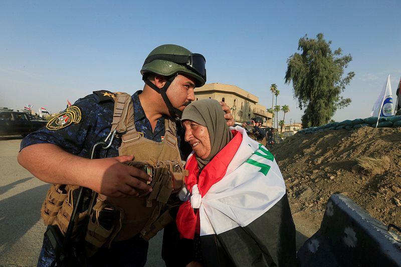 Un policía iraquí besa a una mujer en el oeste de Mosul