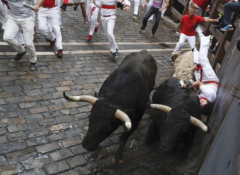 Un mozo ha sufrido un golpe en la curva de Mercaderes en el quinto encierro de los Sanfermines 2017 y ha terminado encima de uno de los toros sin resultar herido por asta