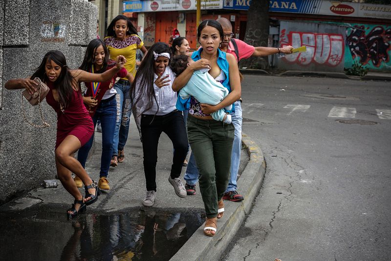 Ciudadanos tratan de evitar los choques entre manifestantes opositores y agentes de la Guardia Nacional Bolivariana.