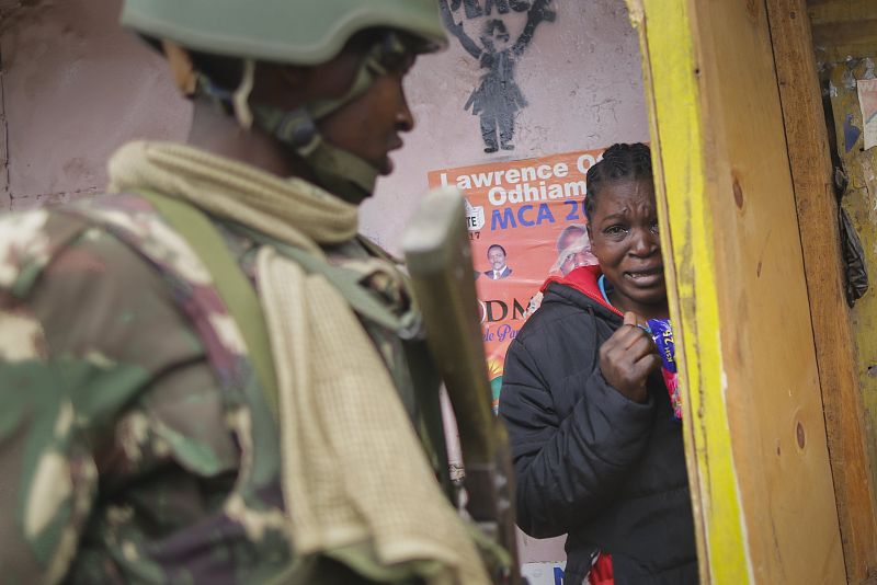 Una mujer aterrorizada se esconde de las revueltas entre partidarios de la oposición y la Policía