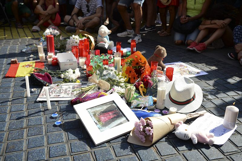 Turistas y ciudadanos se sientan alrededor de las flores para recordar a las víctimas