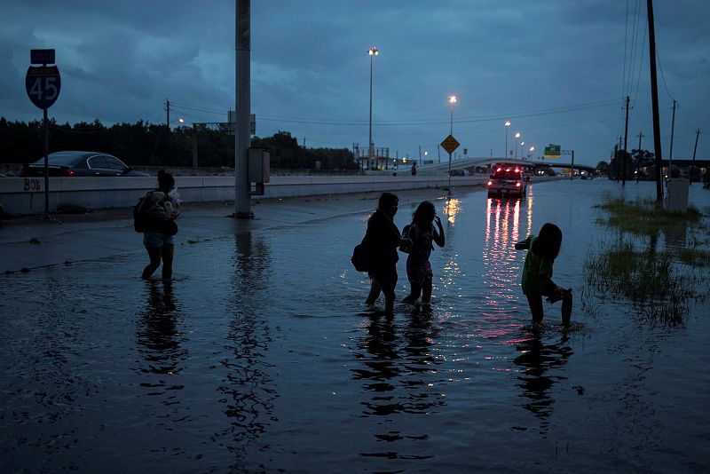 La familia Duong camina en una carretera inundada por el huracán Harvey