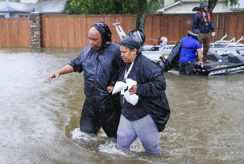 Dos personas caminan por el agua tras ser rescatados de sus casas inundadas por Harvey en Houston