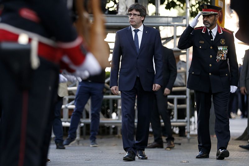 El presidente de la Generalitat, Carles Puigdemont (C), y el jefe de los Mossos, Josep Lluis Trapero (D), durante la ceremonia de ofrenda floral al monumento de Rafael Casanova.