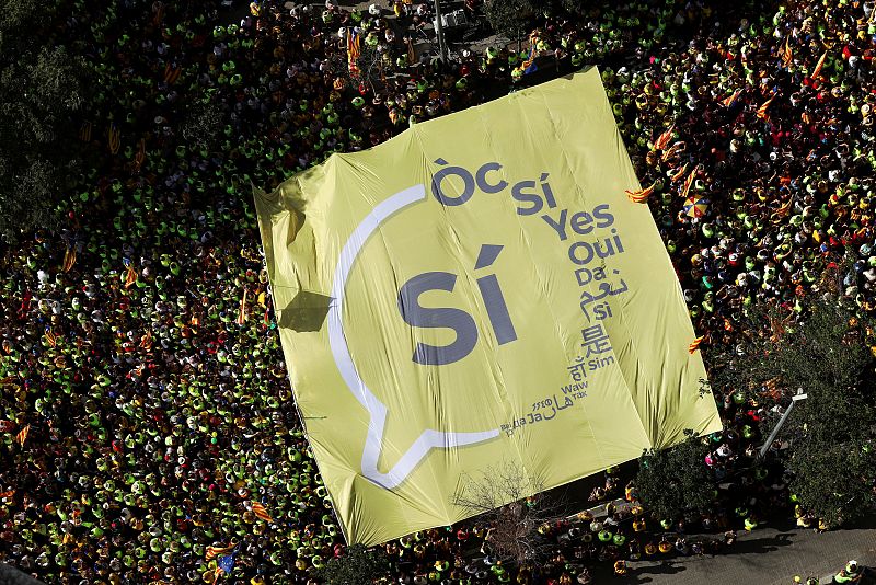 Un cartel con un "SÍ" impreso es llevado por manifestantes independentistas