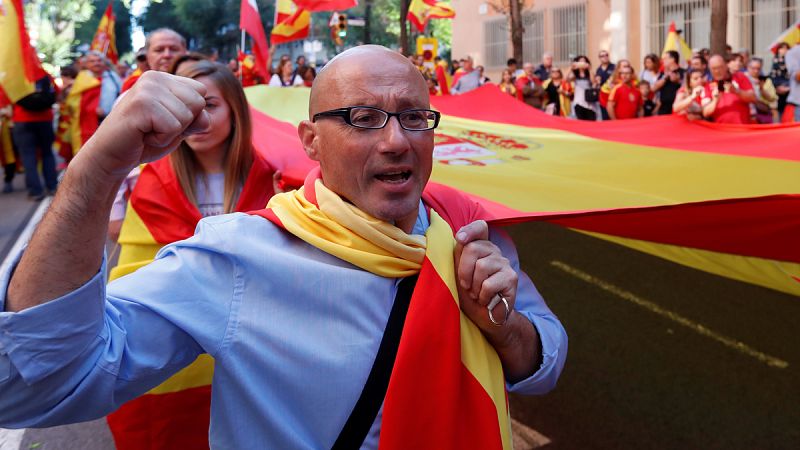 La gente porta una gran bandera de España por las calles de Barcelona