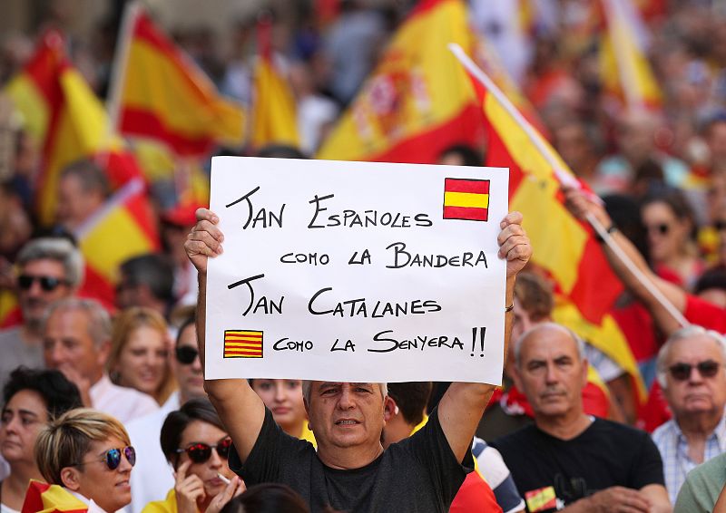 Un hombre muestra una pancarta en la que se puede leer "tan españoles como la bandera, tan catalanes como la senyera"
