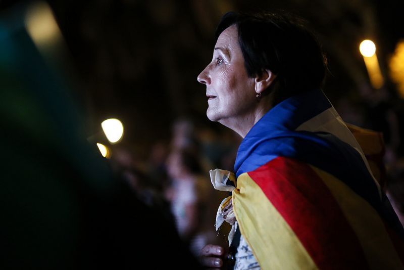 Una mujer espera las palabras del president a través de las pantallas instaladas en el exterior