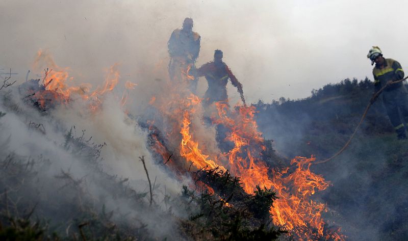 Los bomberos, durante las labores de extinción del incendio que afecta a la parroquia de Cures, Boiro, en la Sierra del Barbanza