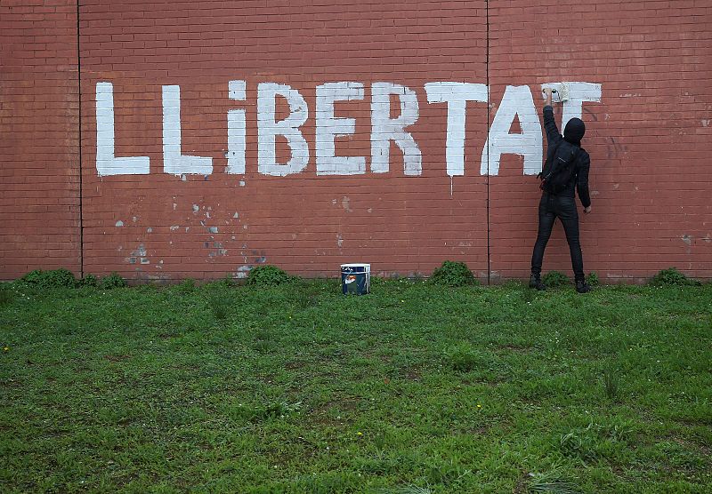 A man paints the word "Freedom" on a wall as protesters blocked a ring road in Barcelona during a partial regional strike in Barcelona