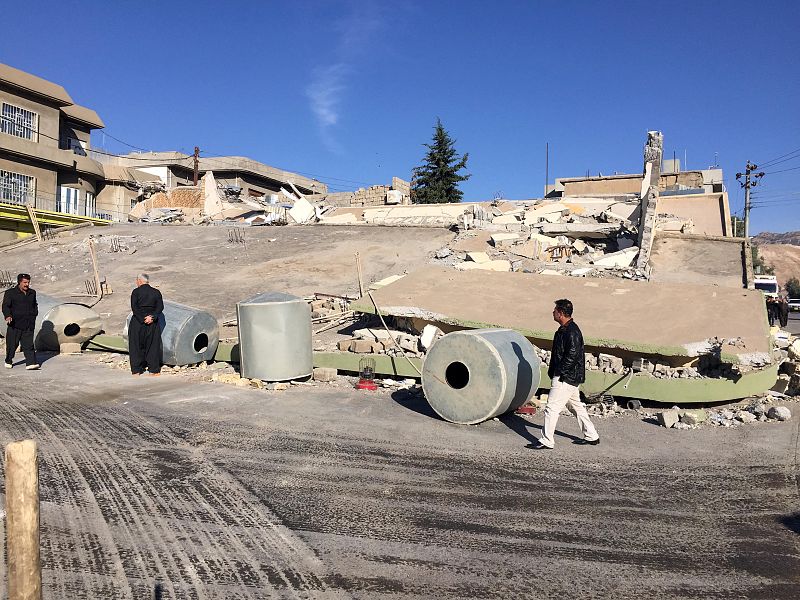 Gente andando junto a un edificio destruido por el terremoto en la ciudad de Darbandikhan, Irak