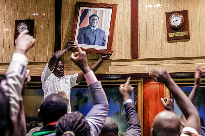 Gente retirando el retrato de Mugabe del Centro Internacional de Conferencias