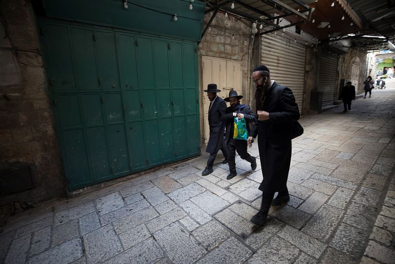Judíos ultraortodoxos caminan por un callejón en Jerusalén donde los comercios permanecen cerrados por la huelga general palestina