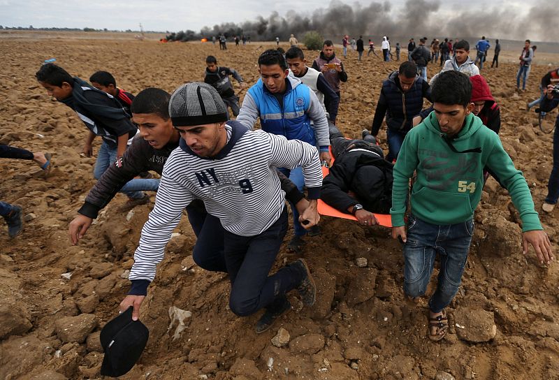 Un grupo de palestinos evacúan a un herido de bala en los enfrentamientos con el Ejército israelí en la frontera de Gaza