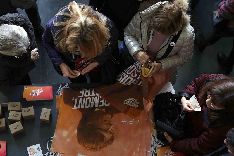 Los asistentes a un acto de campaña de Junts per Catalunya en Mollerussa (Lleida) compran productos de "merchandising" de la candidatura de Carles Puigdemont.