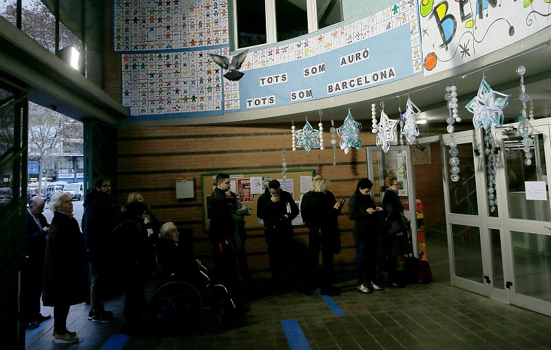 A pigeon flies above people waiting to vote in Catalonia's regional elections at a polling station in Barcelona