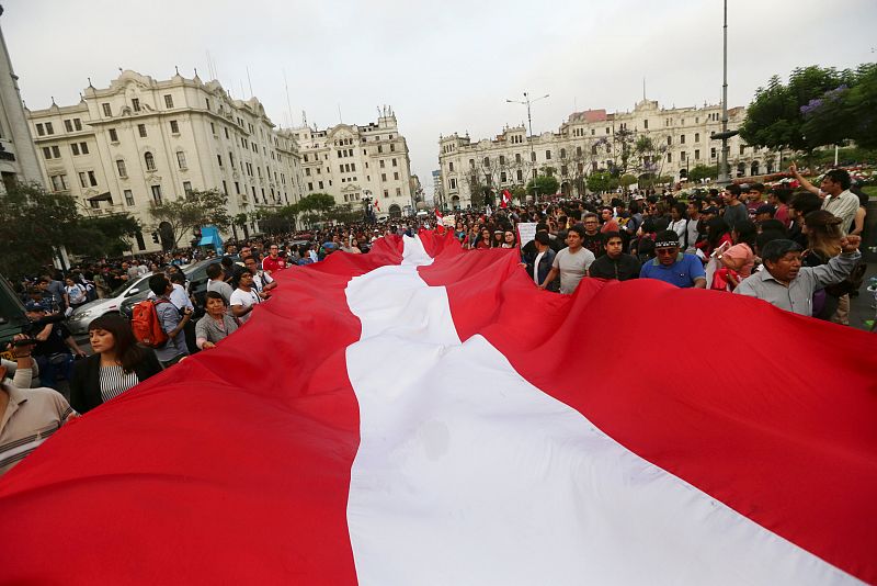 Manifestantes sostienen la bandera peruana