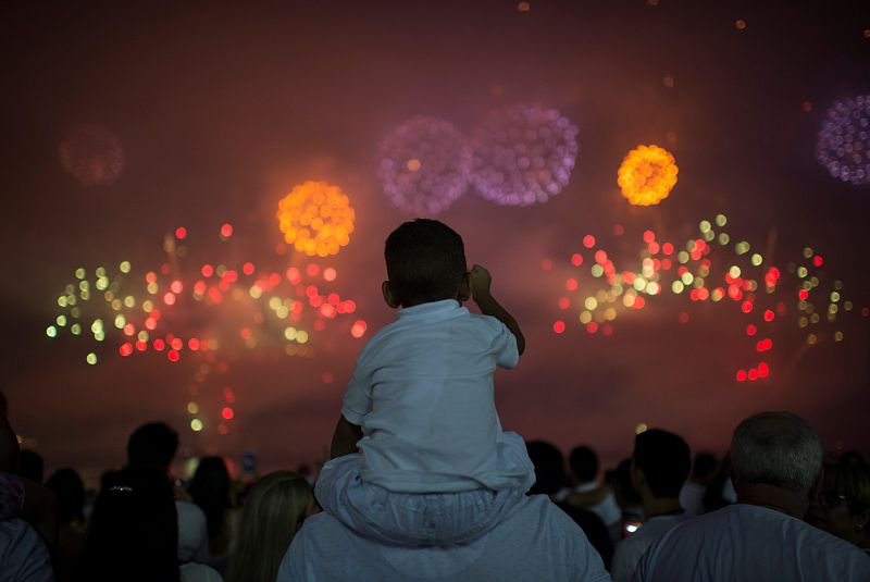 People watch as fireworks explode over Copacabana beach during New Year celebrations in Rio de Janeiro