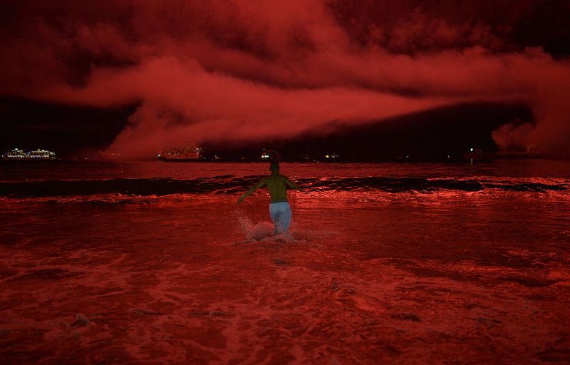 A man runs into the sea as fireworks explode over Copacabana beach during New Year celebrations in Rio de Janeiro, Brazil