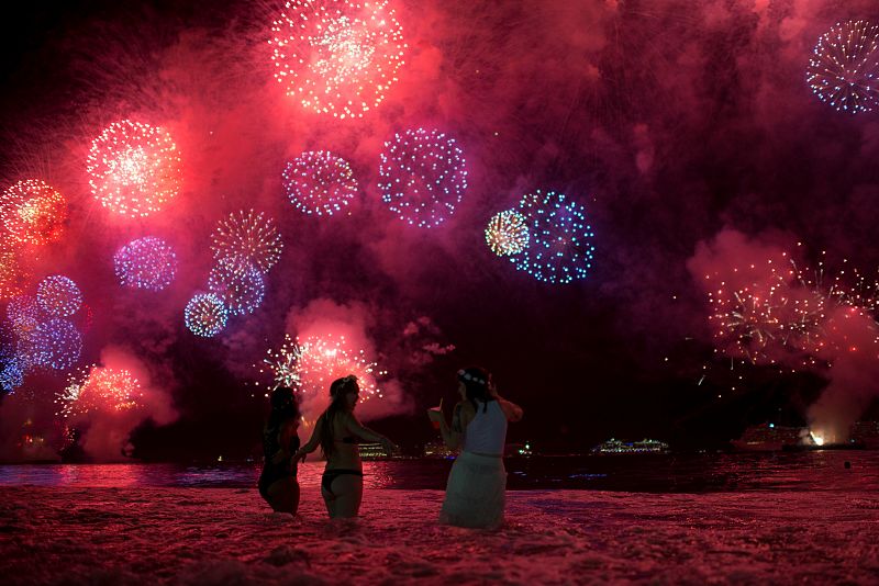 People watch as fireworks explode over Copacabana beach during New Year celebrations in Rio de Janeiro