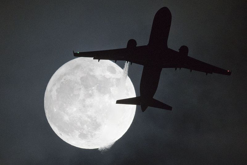 Un avión vuela frente a la superluna o "Luna del lobo", durante su aproximación al aeropuerto de Heathrow.