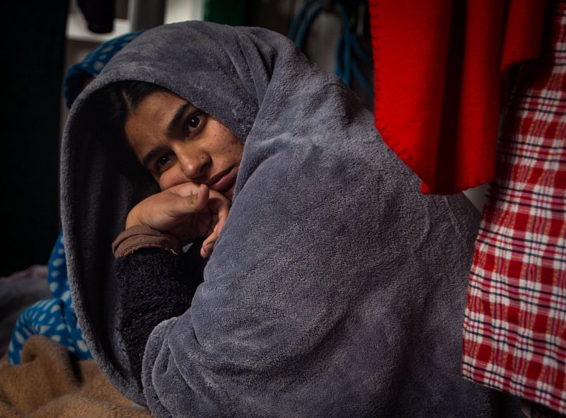 Una de las doce mujeres rescatadas por OPEN ARMS contempla cansada como sus tres hijos juegan