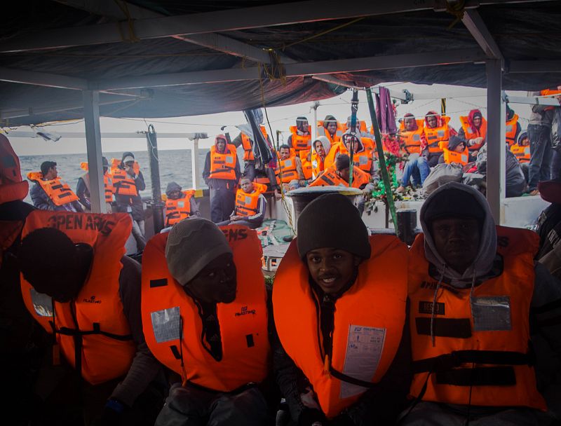 Las personas rescatadas, con los chalecos salvavidas puestos, esperan a ser transferidas al Buque Aquarius de SOS Mediterranée y MSF que les llevará hasta Sicilia