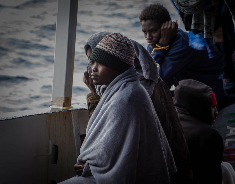 Un grupo de subsaharianos mira al horizonte desde la borda del OPEN ARMS